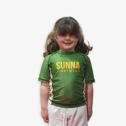 Young child wearing a green Sunna Fightwear rashguard on a white background